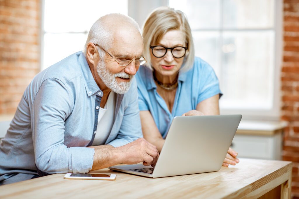 seniorzy siedza przy komputerze i szukaja czegos w internecie